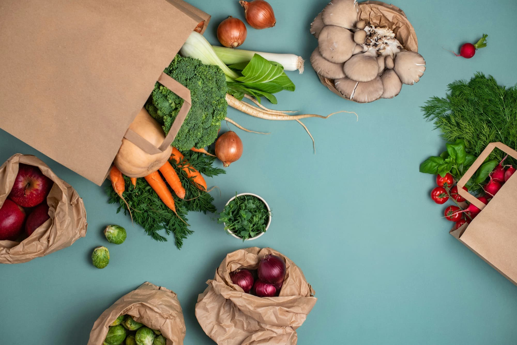 Paper grocery bags spilling over with fresh vegetables